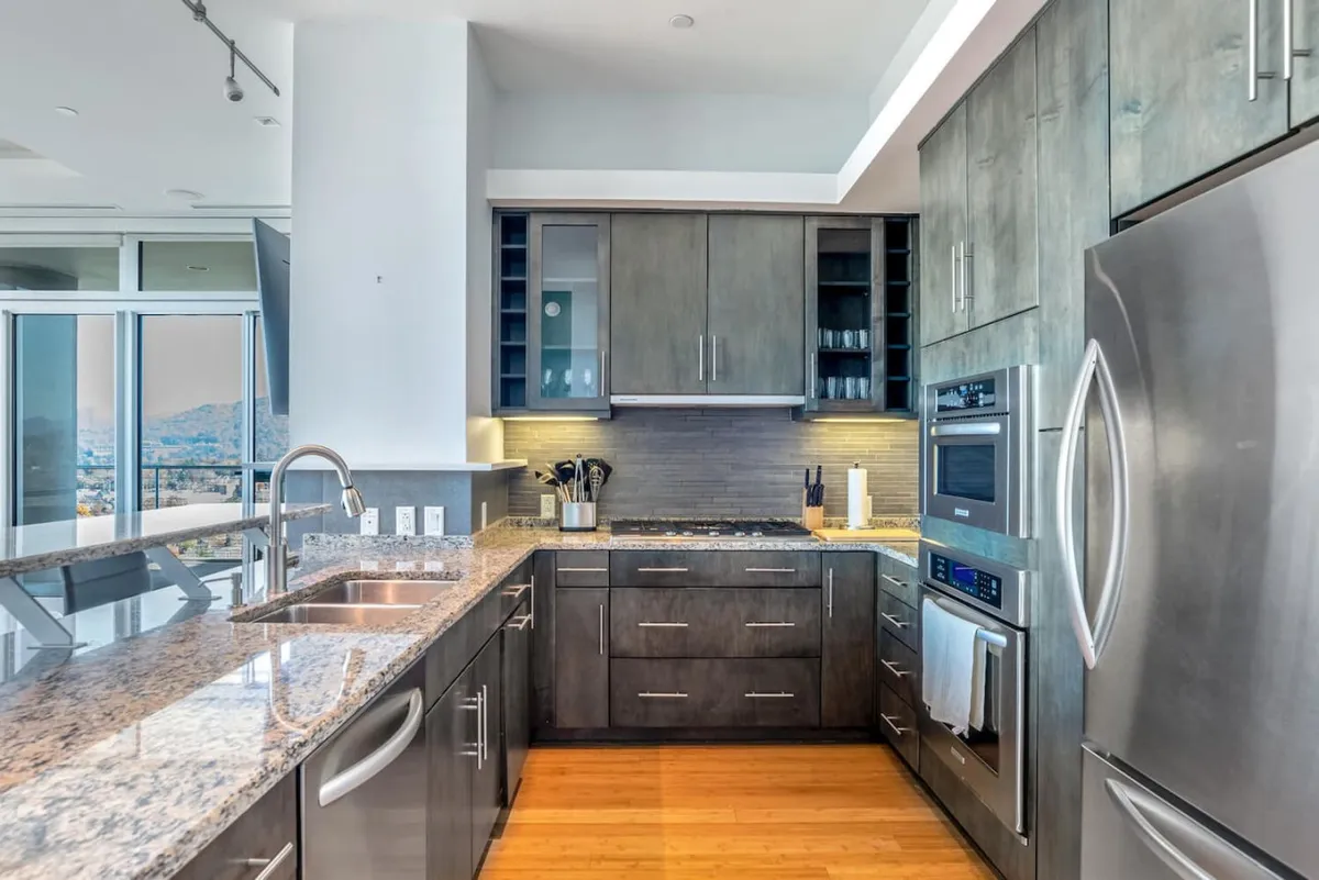 A contemporary kitchen featuring granite countertops, stainless steel appliances, and an open layout with large windows. The space is designed for both cooking and entertaining, with ample counter space and modern finishes that exude sophistication and functionality.