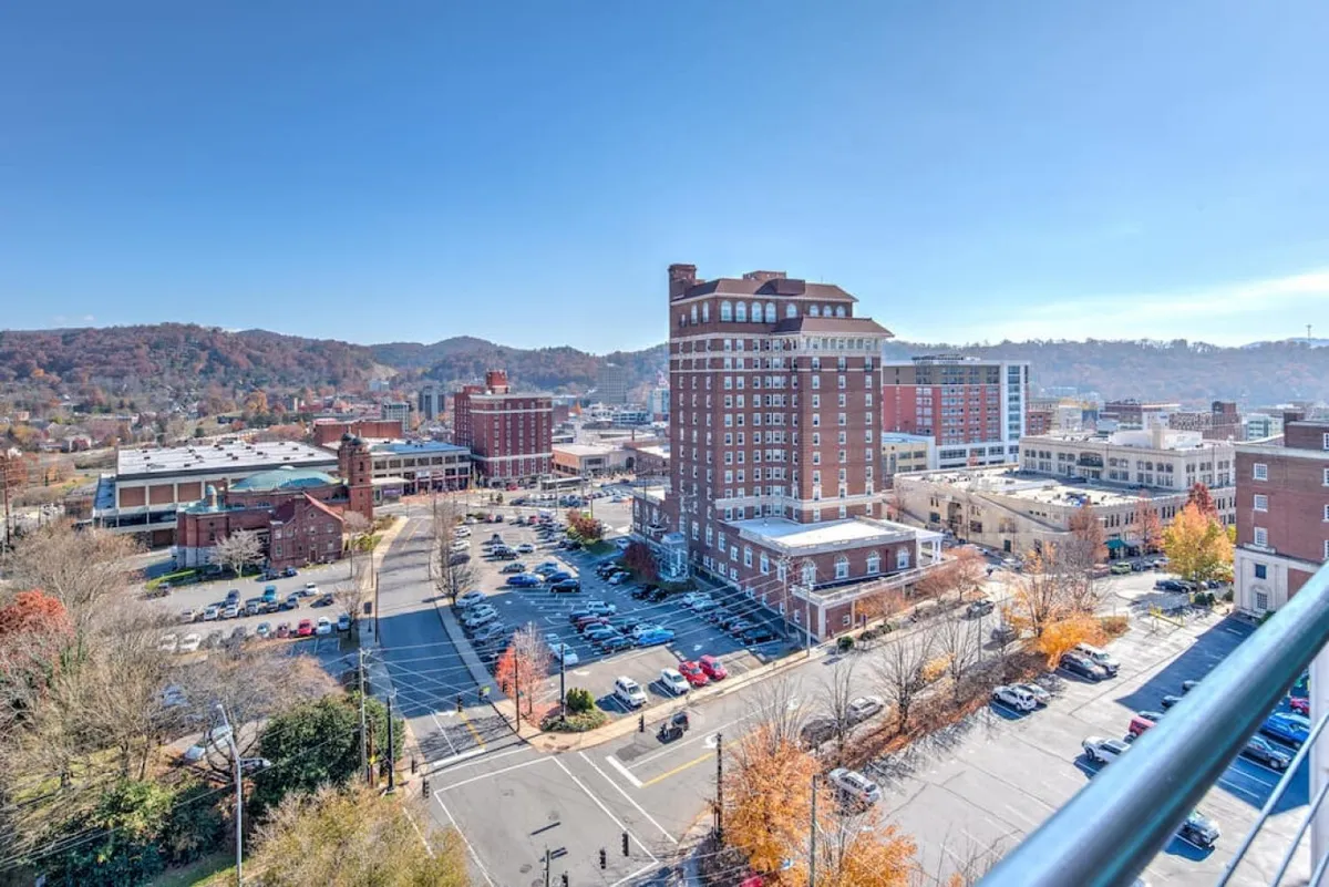 An energetic vista of downtown Asheville, with its lively city streets, historic buildings, and mountain backdrop. The urban scene hints at bustling local life, outdoor cafés, and the promise of exploration just steps away, capturing the vibrancy of the neighborhood.